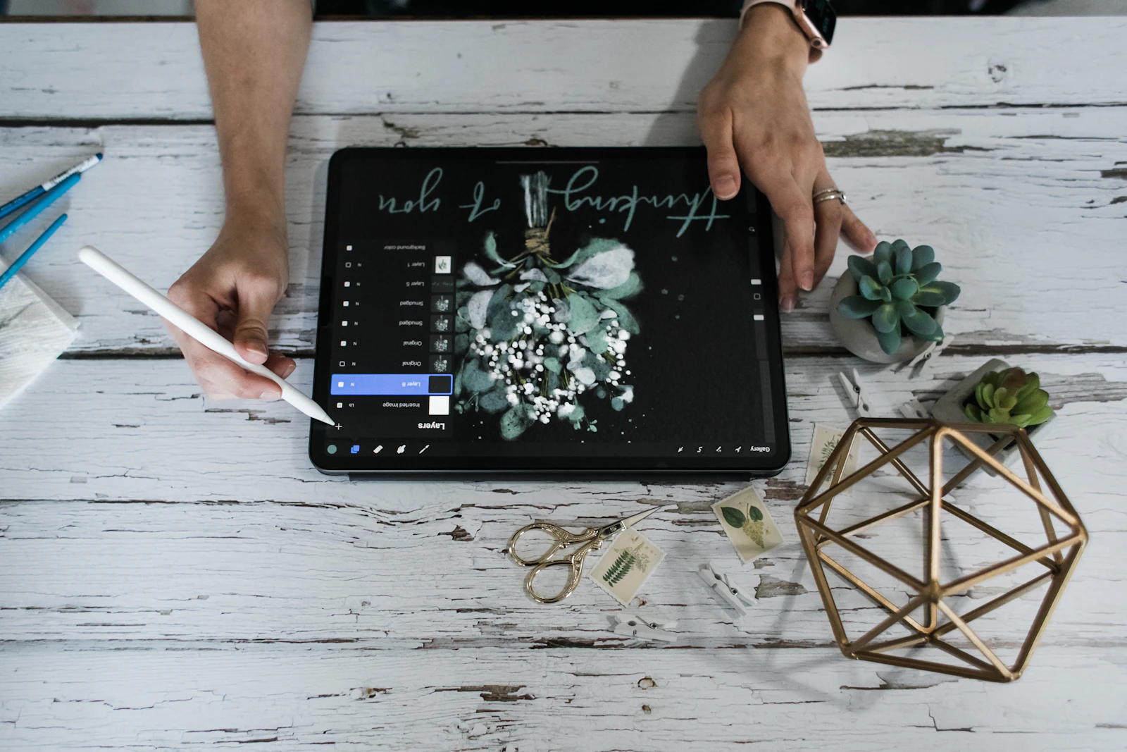 Mains dessinant une composition florale pour le site de mariage sur une tablette avec un stylet