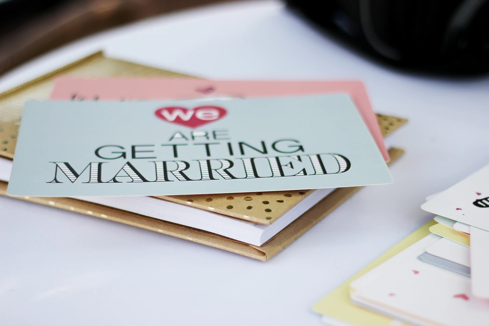 Pila de targetes físiques d’invitació de casament amb el text ‘We are getting married’